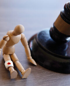 Bandage wrap with blood stain, wooden doll and judge gavel. Personal injury law concept.