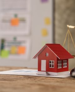 scales of justice, gavel and small wooden toy house, working with documents, signing contract agreements. Real estate law concept.