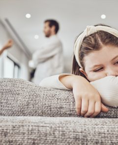 Sad little girl, sofa and parents in conflict, disagreement or fight in the living room at home. Family, divorce and husband in argument with wife and unhappy child on lounge couch in depression